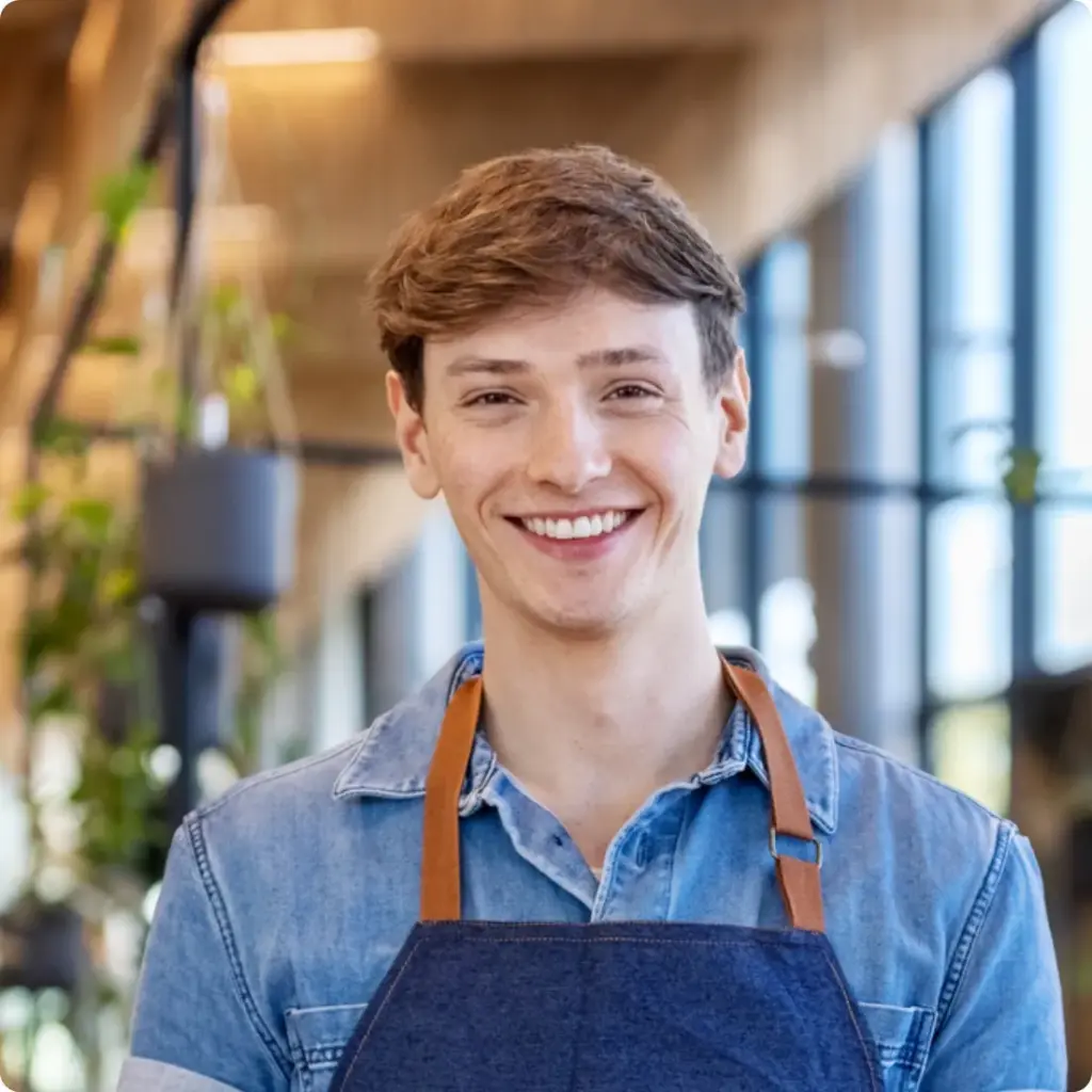 Junger Auszubildender mit Schürze als Symbol für Ausbildung in Gastronomie und Hotellerie